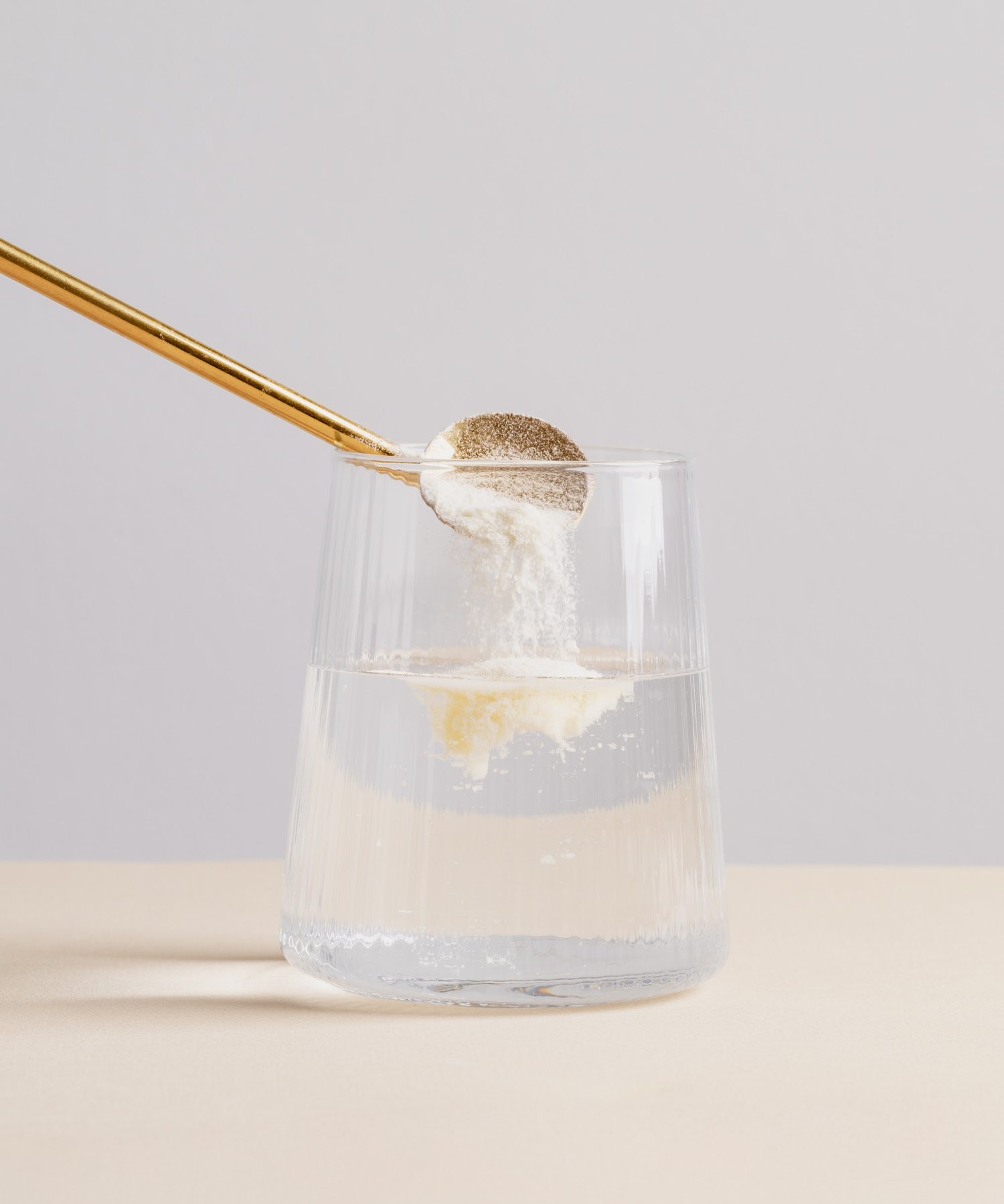 Ein Löffel Kollagenpulver wird in ein Glas Wasser gegeben