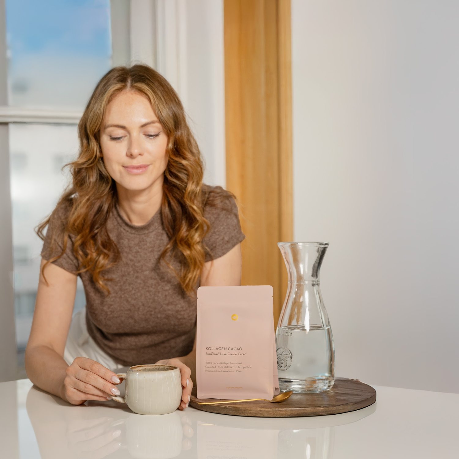 Frau am Tisch trinkt Kollagen Plus SunGlow Luxe aus einer Tasse